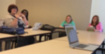 Out of focus photo of several teachers and a laptop
